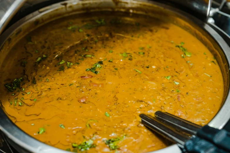 a soup with broth and vegetables is being stirred in a slow cooker