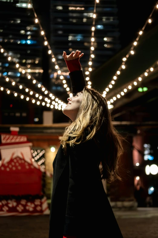 a woman wearing a black coat with her hands up