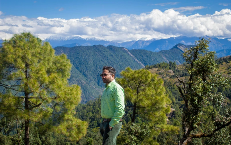 a man in a green shirt stands by some trees