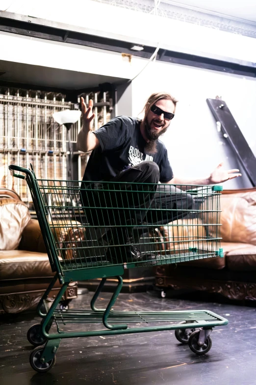 man sitting on top of shopping cart inside of a room