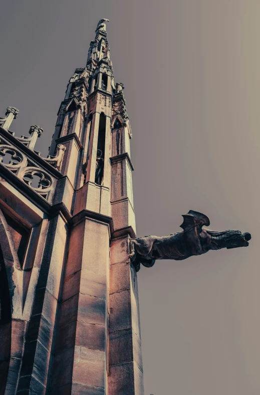 the steeple of an old cathedral with a stone statue in front