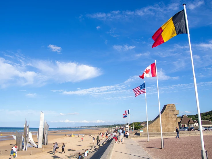 a sandy beach with flags flying high in the air