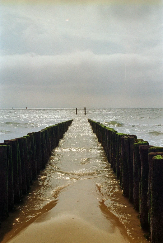 people walk along the sea wall as it breaks away from the beach