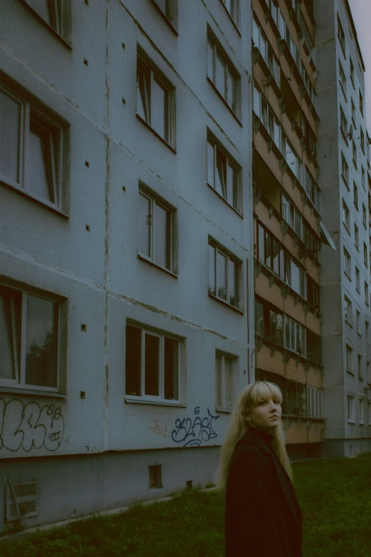 a woman standing in front of an abandoned apartment building