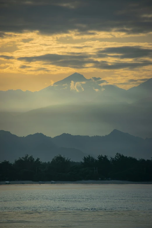 a mountain range with trees and clouds in the background