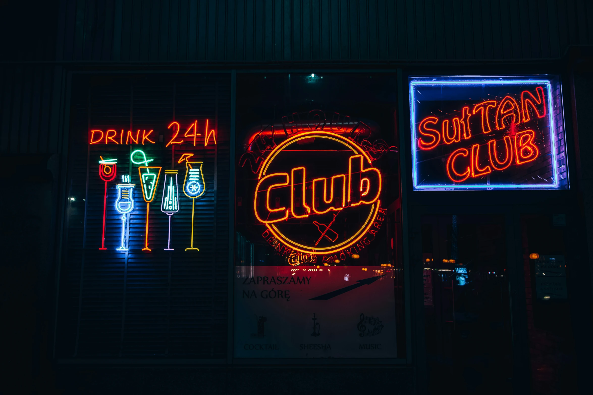 some different colored neon signs hanging outside