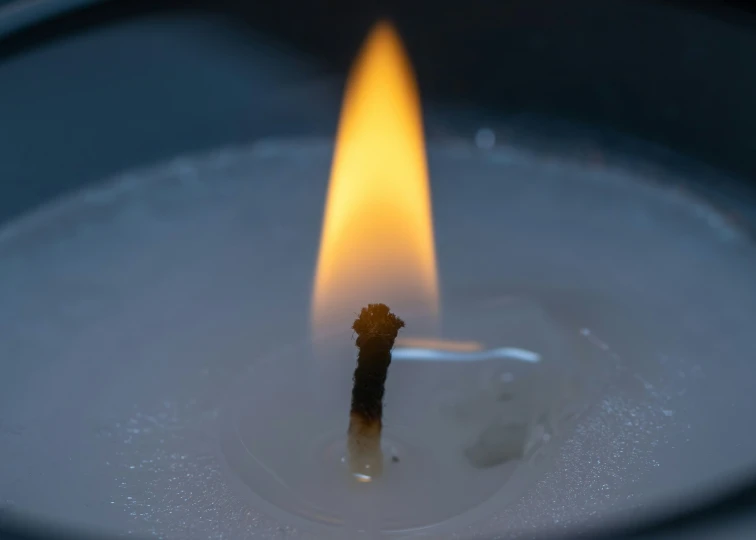 a lit candle in a glass with white liquid