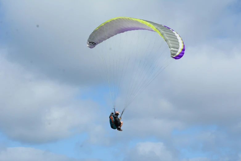 a man with parachutes in mid air against cloudy sky