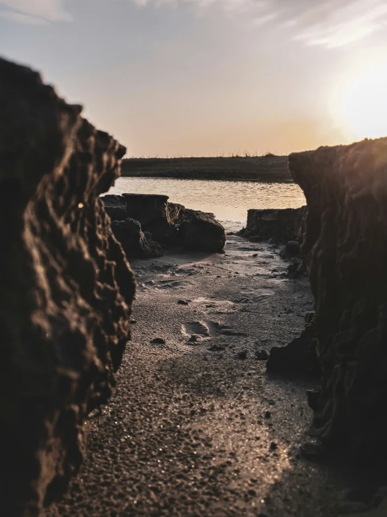 a person walking near the water on rocks and sand