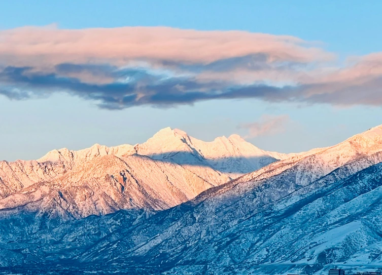 the mountains are covered in snow as the sun is setting