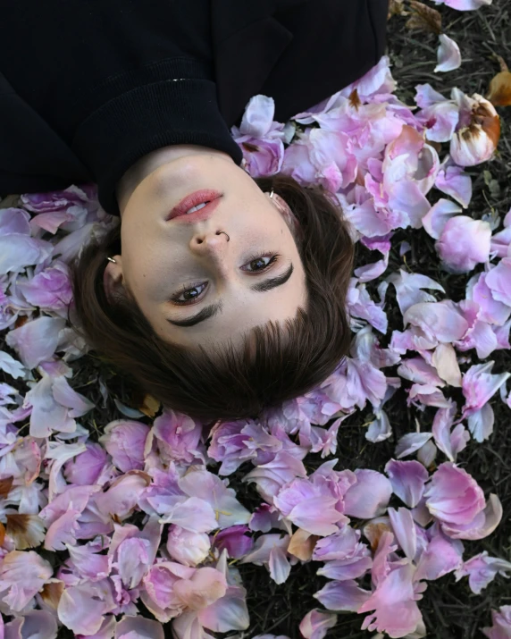 the man is laying down and covered in flowers