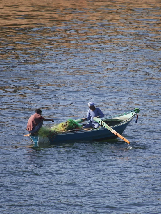 two people sitting on the top of a green boat