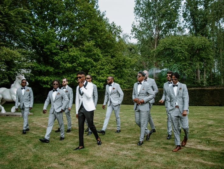 a man in a suit and tie standing on a field next to a group of men