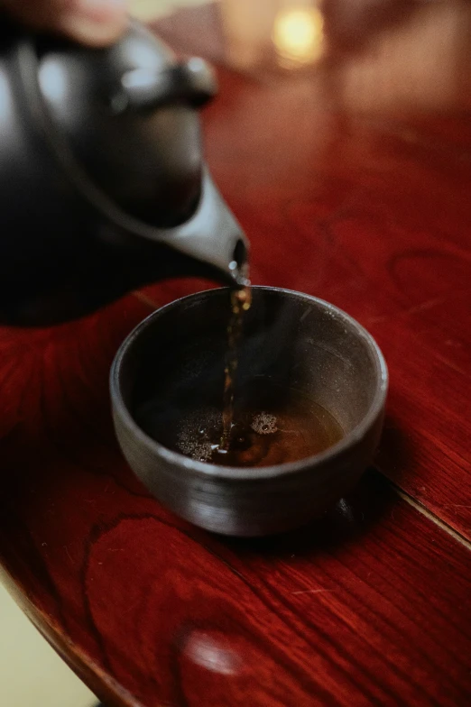 the coffee being poured into a tea kettle on a table