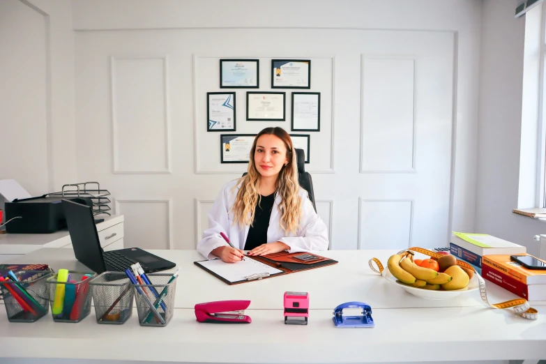 a woman sitting at a desk in front of a laptop and books