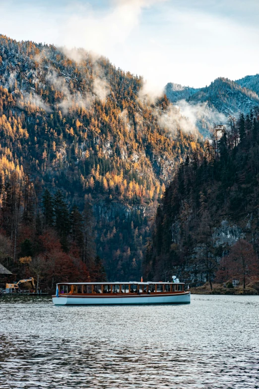 a long boat traveling on the river with mountains in the background