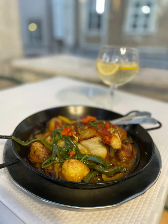 a dish on a plate with a spoon and a glass of wine