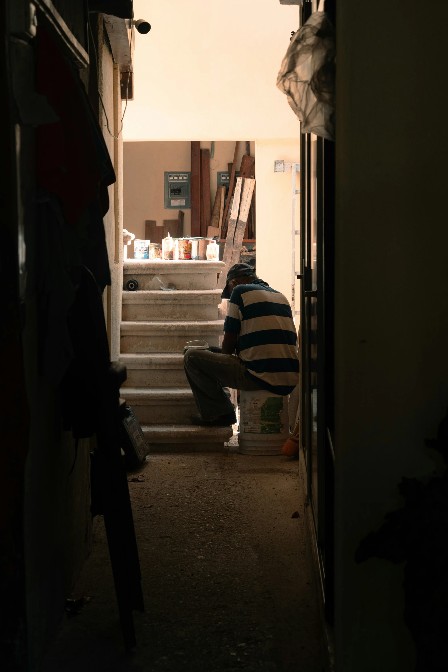 a man kneels down as he looks at the stairs in his house