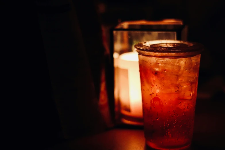 a close up of a drink in a glass near a candle