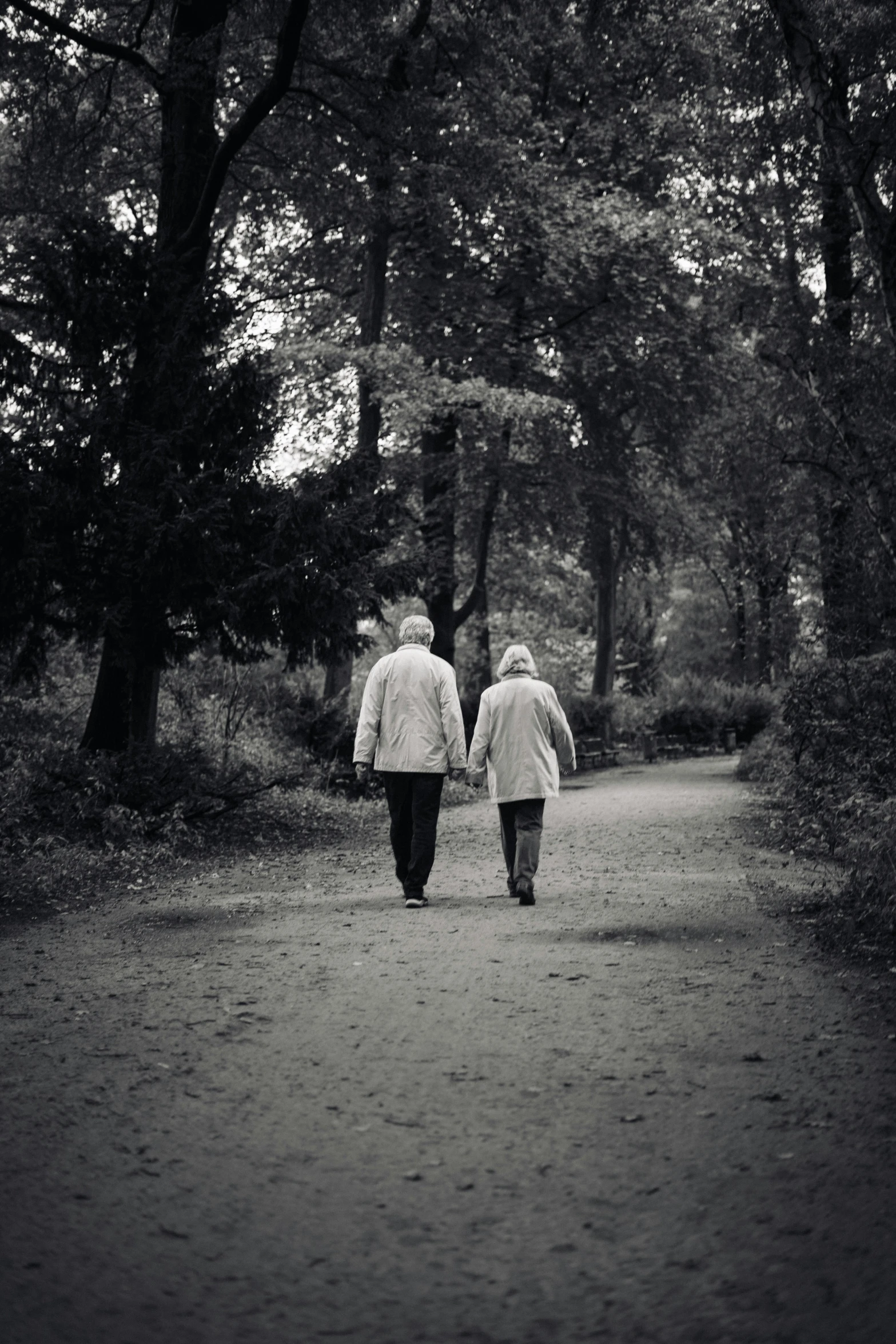 two people walking down a dirt path together