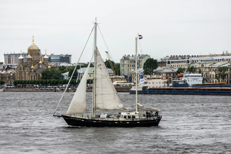 a sail boat on the water in a city harbor