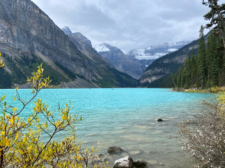 a mountain lake with snow covered mountains and trees around it