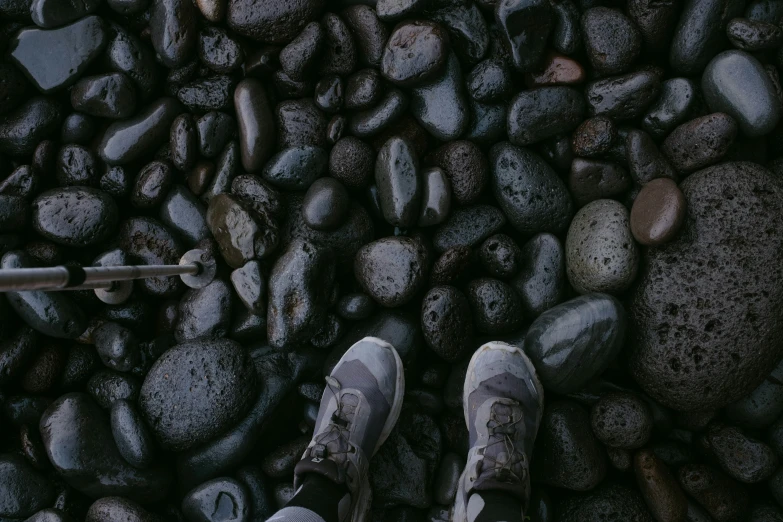 there is a person standing on rocks with white shoes