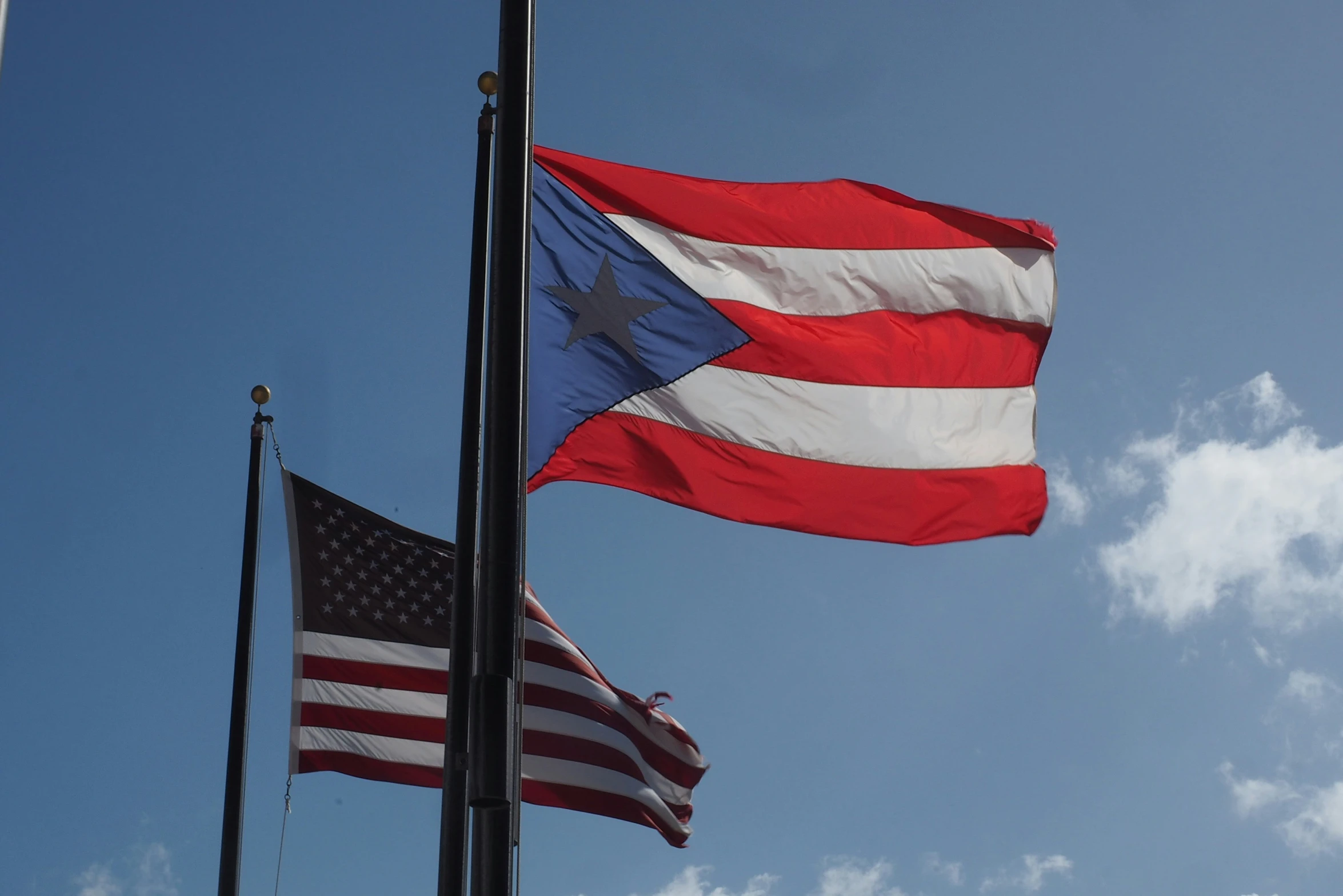 two large flags flying over each other on top of a blue sky