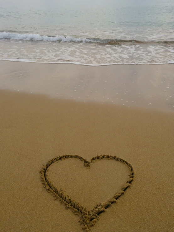 a heart shape drawn in the sand on a beach