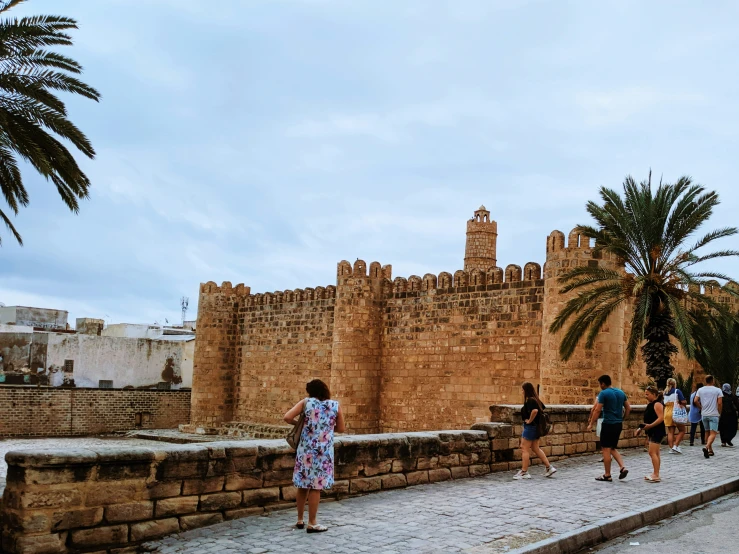 people walking along the cobble stone walls of a city