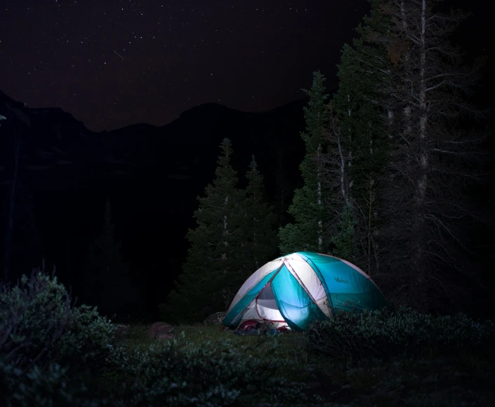 a tent in the woods at night with stars