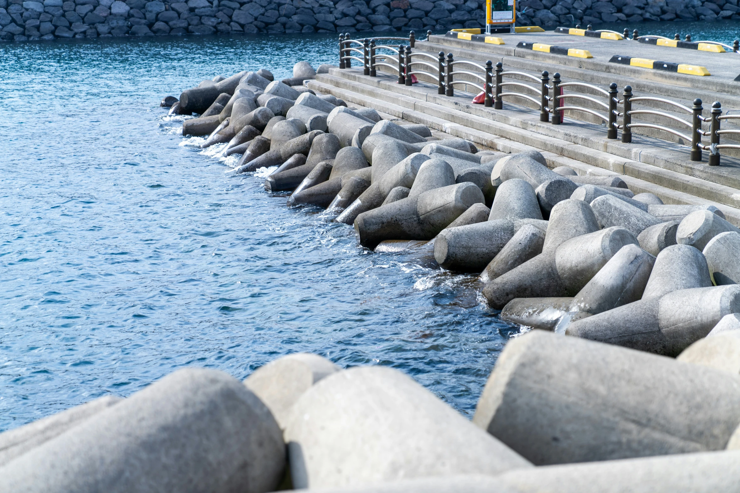 a large concrete barrier is stretching out into the water