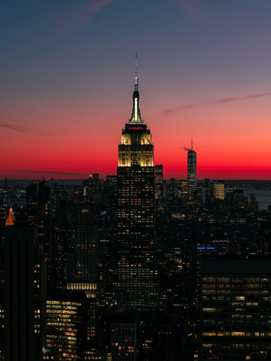 a city skyline as the sun rises with a building lit up