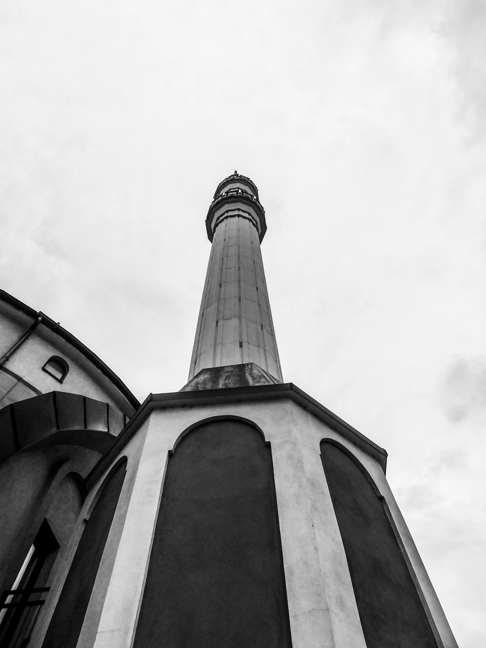 an airplane flying overhead near a tower and another building