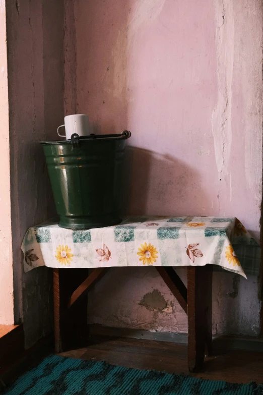 a green pot sitting on a table near a wall