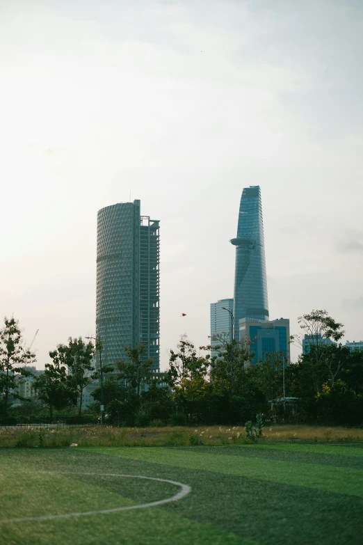 several tall buildings in the distance with a soccer field in front