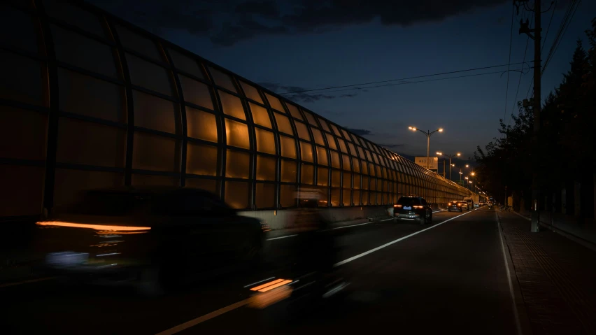 cars are driving down the road next to an illuminated building