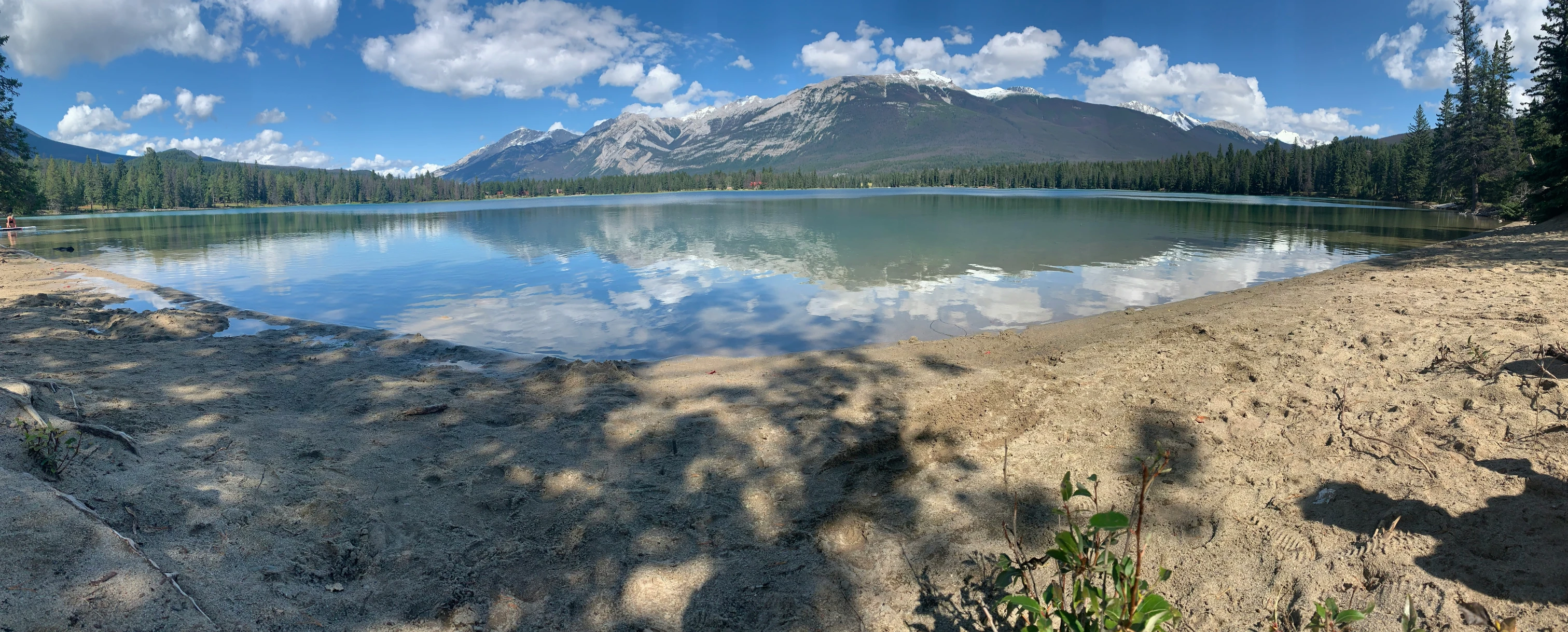 a mountain in the distance with blue sky reflected in a pond