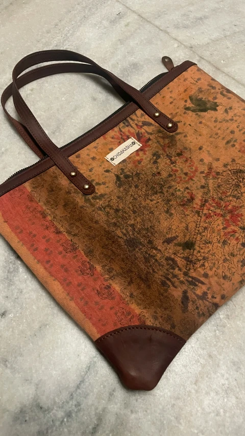 an abstract design leather purse with a brown sued handle