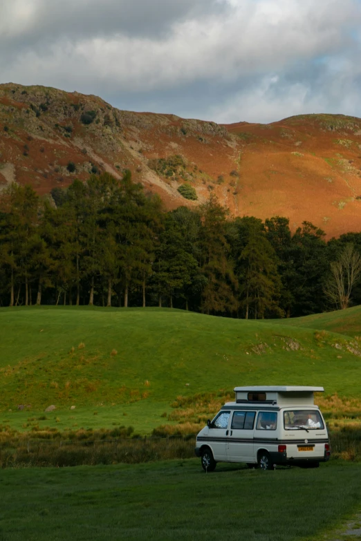 van on a green road and hills in the background