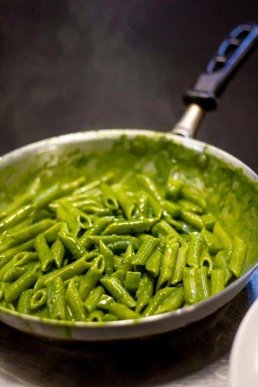 green colored pasta being prepared in a pan