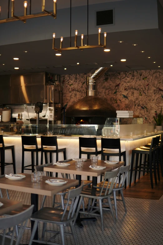 a restaurant with empty tables and chairs and a large oven behind it