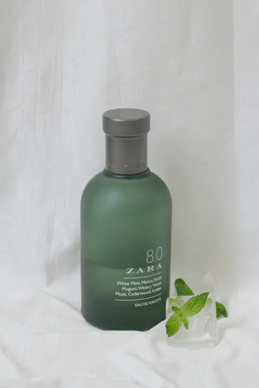 a bottle and green leaves on a white background