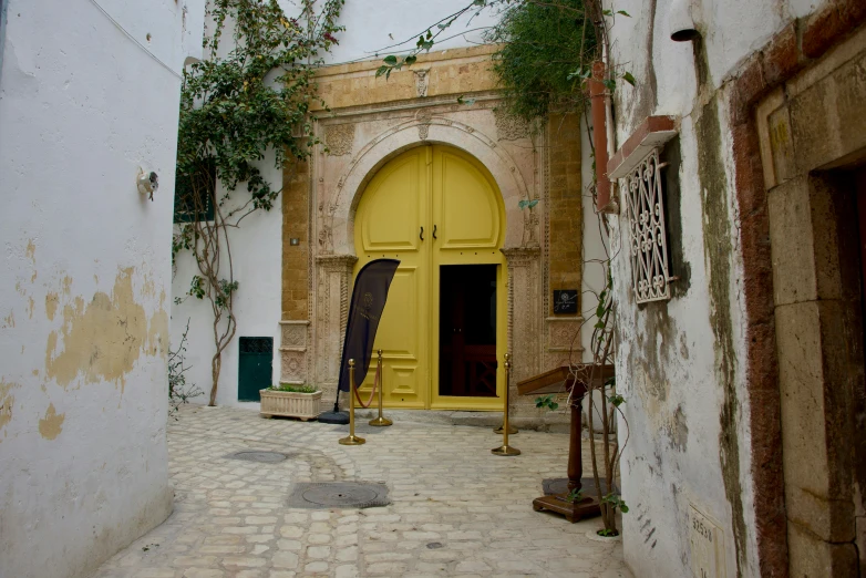 the walkway in front of an old building leads into a yellow door