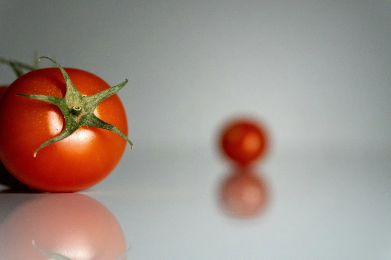 a couple of tomatoes on a table next to a green leaf