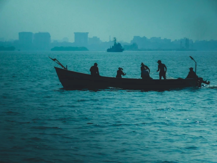 a rowboat with several men in the front of it going out on a foggy day