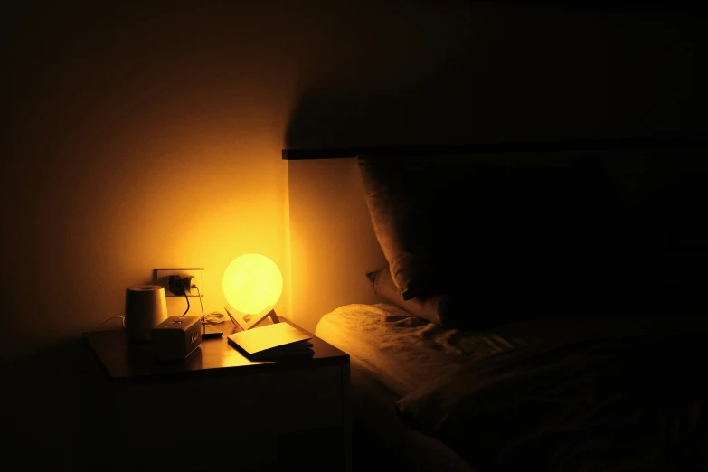 a bed in a dark room with a lamp on