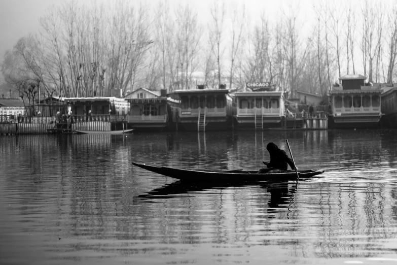 a person paddling in a boat with houses on the lake behind them