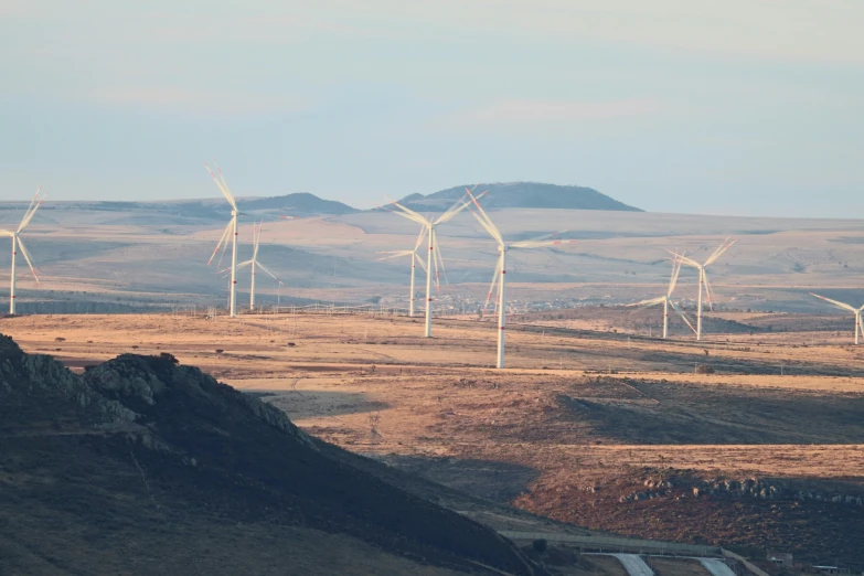 many windmills on a hilly field with a clear sky