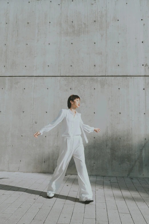 a woman with dark hair and white clothes is walking